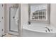 Bright bathroom with a standalone shower and a large soaking tub under a window at 4024 Dunkirk Dr, Burlington, NC 27215