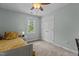 Bright bedroom features tan carpet, a ceiling fan, double closet doors and a window overlooking the trees at 4225 Old Lewis Farm Rd, Raleigh, NC 27604