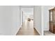 Hallway leading to a bright living room featuring wood floors, white walls, and a glimpse of a cozy seating area at 482 Olivia Crossing Ct, Four Oaks, NC 27524