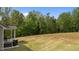 Expansive backyard featuring a grill and outdoor seating on a covered patio with lush, mature trees at 5 Cinnamon Teal Way, Youngsville, NC 27596