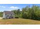 Large backyard with lush trees surrounding a charming house with a covered porch, perfect for relaxing outdoors at 5 Cinnamon Teal Way, Youngsville, NC 27596