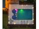 Aerial view of a backyard pool with sun loungers, umbrellas, lush landscaping and illuminated by landscape lighting at 5125 Avalaire Oaks Dr, Raleigh, NC 27614