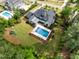 Aerial shot showcasing a beautiful home, pool, well-manicured lawn, and outdoor playground in a serene setting at 5125 Avalaire Oaks Dr, Raleigh, NC 27614