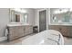 Bright bathroom featuring double vanities, soaking tub, gray cabinets, and modern fixtures at 5125 Avalaire Oaks Dr, Raleigh, NC 27614