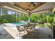 Covered patio with dining table, ceiling fan, grill, and view of the pool and backyard at 5125 Avalaire Oaks Dr, Raleigh, NC 27614