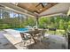 Covered patio with dining table and view of the backyard and pool with umbrellas at 5125 Avalaire Oaks Dr, Raleigh, NC 27614