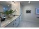 Well-lit bathroom with double sinks, white cabinets, granite countertops, and modern fixtures at 5906 Dunzo Dr, Raleigh, NC 27617
