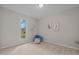 Bright, carpeted bedroom featuring a large window, blue ottoman and a soft color palette at 623 Lincoln Dr, Kenly, NC 27542