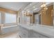 Bright and airy bathroom featuring a soaking tub, white cabinetry, and detailed wall sconces at 708 Mill Pointe Way, Elon, NC 27244