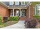 Inviting front porch with brick steps, rocking chairs, white columns, and lovely garden at 708 Mill Pointe Way, Elon, NC 27244