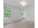 Well-lit bedroom with neutral carpet, white walls, and windows overlooking a verdant landscape at 8004 Mill Bluff Ct, Raleigh, NC 27616