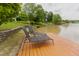 Two lounge chairs sit on a wooden pier overlooking the water and the beautiful trees around the area at 1003 Southshore Pkwy, Durham, NC 27703