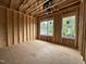 Unfinished bedroom with exposed framework and window openings providing a view of the surrounding neighborhood at 1523 1/2 Sunrise Ave, Raleigh, NC 27608