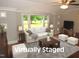 Bright living room with large windows and a comfortable white sofa. (Virtually Staged) at 1610 W B St, Butner, NC 27509