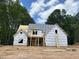 A partially constructed two-story home stands against a backdrop of mature trees and a bright blue sky with scattered clouds at 194 Landon Ridge, Sanford, NC 27330