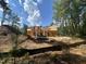 A view of a home under construction from a lower angle shows exposed framing surrounded by mature trees at 194 Landon Ridge, Sanford, NC 27330