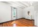 Sunlit bedroom with hardwood floors, white walls, and a dresser underneath a window at 2440 Glencoe St, Burlington, NC 27217