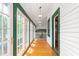 Bright hallway featuring wood flooring, white walls, a white ceiling, and green trim on the french doors at 2440 Glencoe St, Burlington, NC 27217