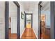 Hallway featuring hardwood floors, classic white walls, and doorway views to multiple rooms at 2440 Glencoe St, Burlington, NC 27217