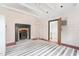 Living room featuring a brick fireplace with a black hearth, wood floors, white walls, and open door at 2440 Glencoe St, Burlington, NC 27217
