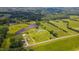 Expansive aerial view showcases the home's picturesque setting amidst green fields and a tranquil pond at 2912 Epps Clark Rd, Siler City, NC 27344