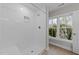 Bright white walk-in shower with tile surround, shower head, and seat with a view to the outside at 408 W Stallings St, Clayton, NC 27520