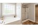 Bright bathroom showcasing a large soaking tub under a window and a separate glass-enclosed shower at 4509 Joe Cotton Dr, Knightdale, NC 27545