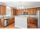 Well-lit kitchen with stainless appliances, a half wall, and abundant wood cabinetry at 4509 Joe Cotton Dr, Knightdale, NC 27545