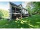 Exterior view of home featuring a manicured lawn, deck, screened-in porch, and mature trees at 5025 Martin Farm Rd, Raleigh, NC 27613