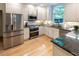 Well-lit kitchen featuring stainless steel appliances, stone backsplash, and light wood floors at 5025 Martin Farm Rd, Raleigh, NC 27613