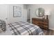Bedroom with plaid bedding, wood dresser, round mirror, and decorative wall art at 648 White Birch Ln, Angier, NC 27501