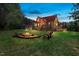 Spacious backyard featuring a fire pit, Adirondack chairs, and a charming log home surrounded by trees at 6707 Frieden Church Rd, Gibsonville, NC 27249