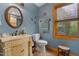 Powder blue bathroom featuring a decorative vanity, framed mirror and window at 6707 Frieden Church Rd, Gibsonville, NC 27249