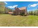 Exterior shot of a log cabin-style house with a red roof, set in a large, grassy yard at 6707 Frieden Church Rd, Gibsonville, NC 27249