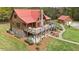 Stunning log home with a red roof, large deck, stone accents, and beautifully landscaped yard at 6707 Frieden Church Rd, Gibsonville, NC 27249