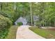 Charming gray home with a concrete driveway nestled in a lush, wooded landscape at 7116 Asheway Dr, Holly Springs, NC 27540