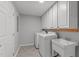 Well-lit laundry room is complete with overhead cabinets, washer, dryer, and utility sink at 7116 Asheway Dr, Holly Springs, NC 27540