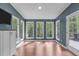 Blue sun room featuring wood floors, white trim, and wall-to-wall windows overlooking the yard at 7116 Asheway Dr, Holly Springs, NC 27540
