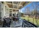 Expansive covered back porch with stone flooring, multiple seating areas, and views of the manicured yard at 7516 Orchard Crest Ct, Apex, NC 27539