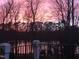 A tranquil view of the lake surrounded by trees at sunset from the backyard at 7516 Orchard Crest Ct, Apex, NC 27539
