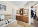 A bathroom featuring a soaking tub with tile surround, double vanity, and decorative mirrors at 7516 Orchard Crest Ct, Apex, NC 27539