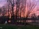 View of the lake at dusk with colorful sky and trees at 7516 Orchard Crest Ct, Apex, NC 27539