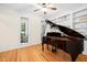 Elegant living room featuring hardwood floors, built-in shelves, and a grand piano at 7516 Orchard Crest Ct, Apex, NC 27539