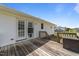Exterior shot of the home's backyard deck, featuring weathered planks, a set of French doors, and partial shade at 8163 Julian Rd, Dunn, NC 28334