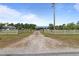 Long driveway leads to a charming home with a blue metal roof, surrounded by lush greenery at 8163 Julian Rd, Dunn, NC 28334