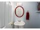 Elegant powder room featuring an oval mirror, pedestal sink, and decorative light fixture at 8908 Shallcross Way, Raleigh, NC 27617