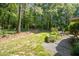 Large wooded backyard featuring a low-wall garden with various plants, flowers, and a stone patio at 10011 Hammock Bnd, Chapel Hill, NC 27517