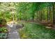 Wooded backyard with small grass lawn and a small patio area with a small garden box at 10011 Hammock Bnd, Chapel Hill, NC 27517