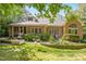 Spacious backyard with a brick house backdrop, manicured lawn, and a charming flower garden at 10011 Hammock Bnd, Chapel Hill, NC 27517