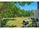 View of spacious backyard with mature trees, a deck, and outdoor grilling area at 109 N Valley Dr, Louisburg, NC 27549